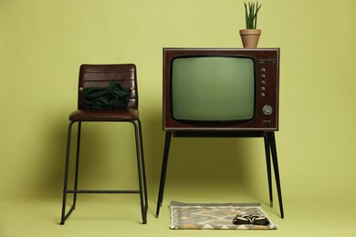 Photo of Retro TV set and other used stuff on olive background