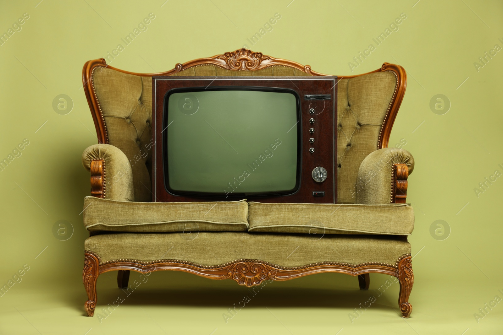 Photo of Retro TV set and sofa on olive background. Used stuff