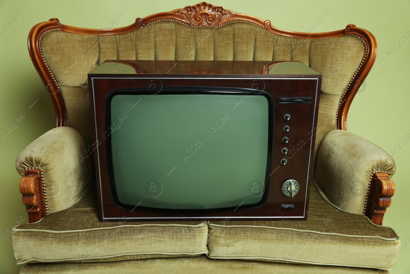 Retro TV set and sofa on olive background, closeup. Used stuff Photo of Retro TV set and sofa on olive background, closeup. Used stuff