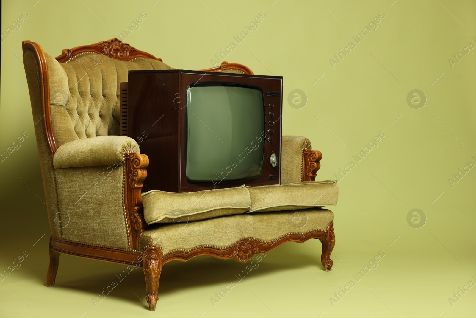Retro TV set and sofa on olive background, space for text. Used stuff Photo of Retro TV set and sofa on olive background, space for text. Used stuff