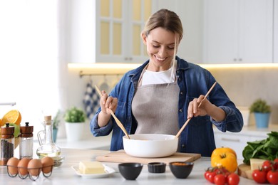 Photo of Smiling woman cooking at table in kitchen