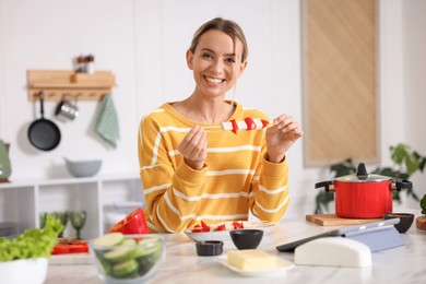 Photo of Smiling woman with tasty skewers after cooking at table in kitchen