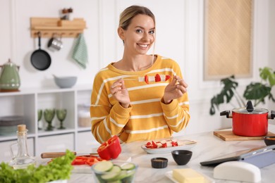 Photo of Smiling woman with tasty skewers after cooking at table in kitchen