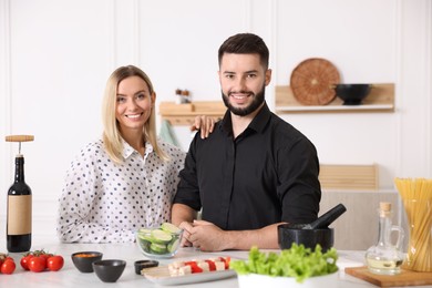 Photo of Happy couple cooking together at table in kitchen