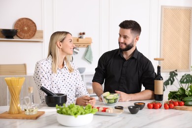 Photo of Happy couple cooking together at table in kitchen