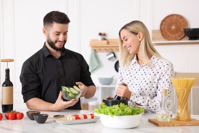 Photo of Happy couple cooking together at table in kitchen