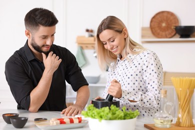 Photo of Happy couple cooking together at table in kitchen