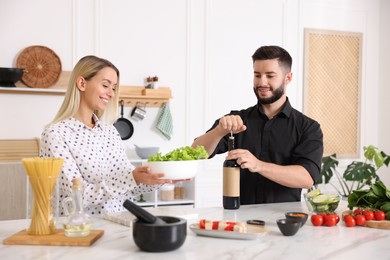 Photo of Smiling man opening bottle of wine while cooking with his wife at table in kitchen