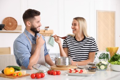 Photo of Happy couple cooking together at table in kitchen