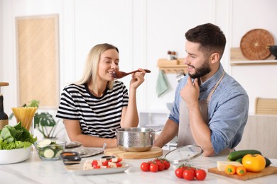 Photo of Happy couple cooking together at table in kitchen