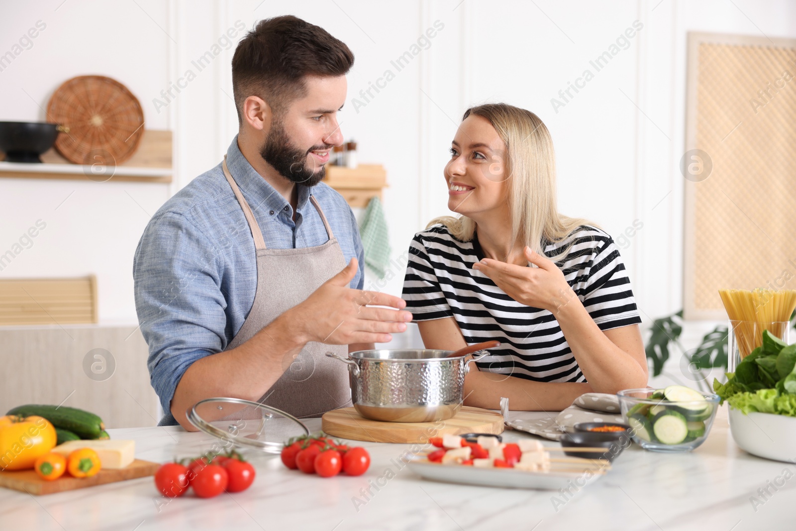 Photo of Happy couple cooking together at table in kitchen