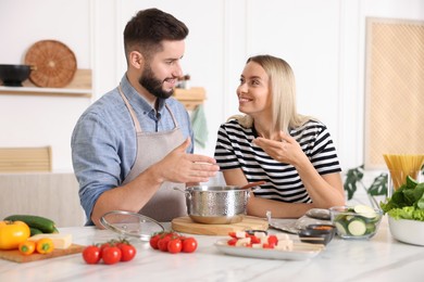 Photo of Happy couple cooking together at table in kitchen