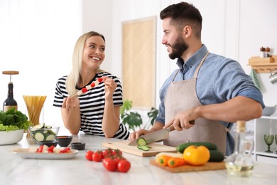 Photo of Happy couple cooking together at table in kitchen