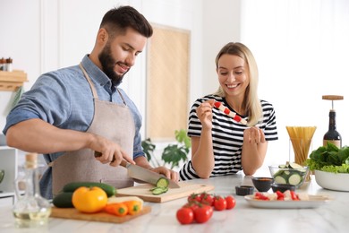 Photo of Happy couple cooking together at table in kitchen