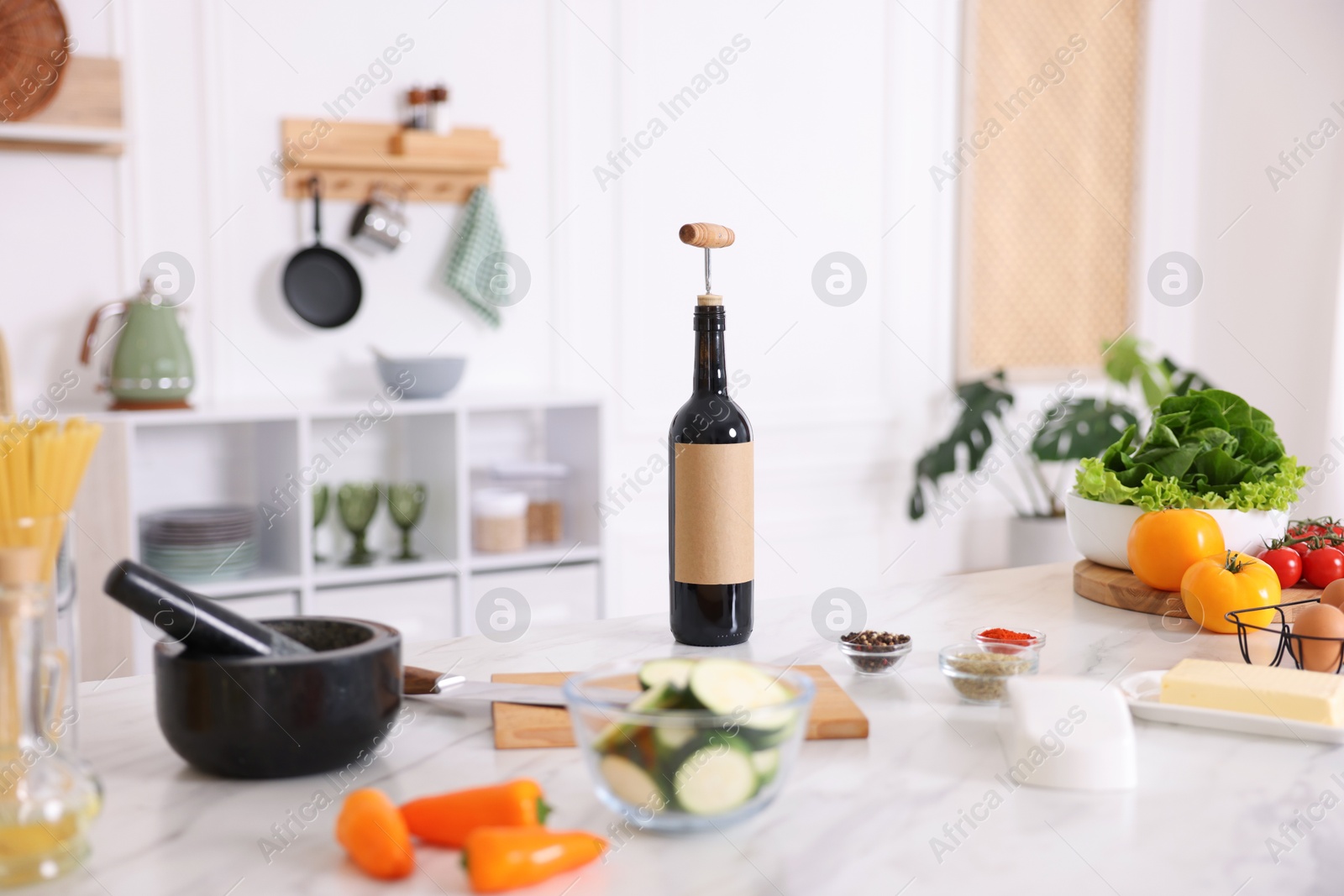Photo of Cooking process. Bottle of wine and products on marble table in kitchen, closeup