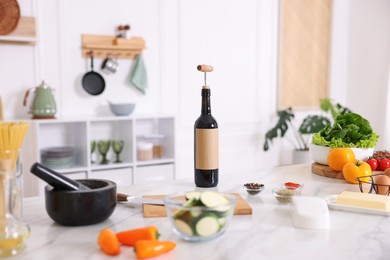 Photo of Cooking process. Bottle of wine and products on marble table in kitchen, closeup