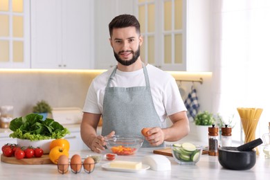 Photo of Smiling man cooking at table in kitchen