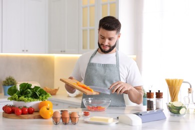 Photo of Young man cooking at table in kitchen