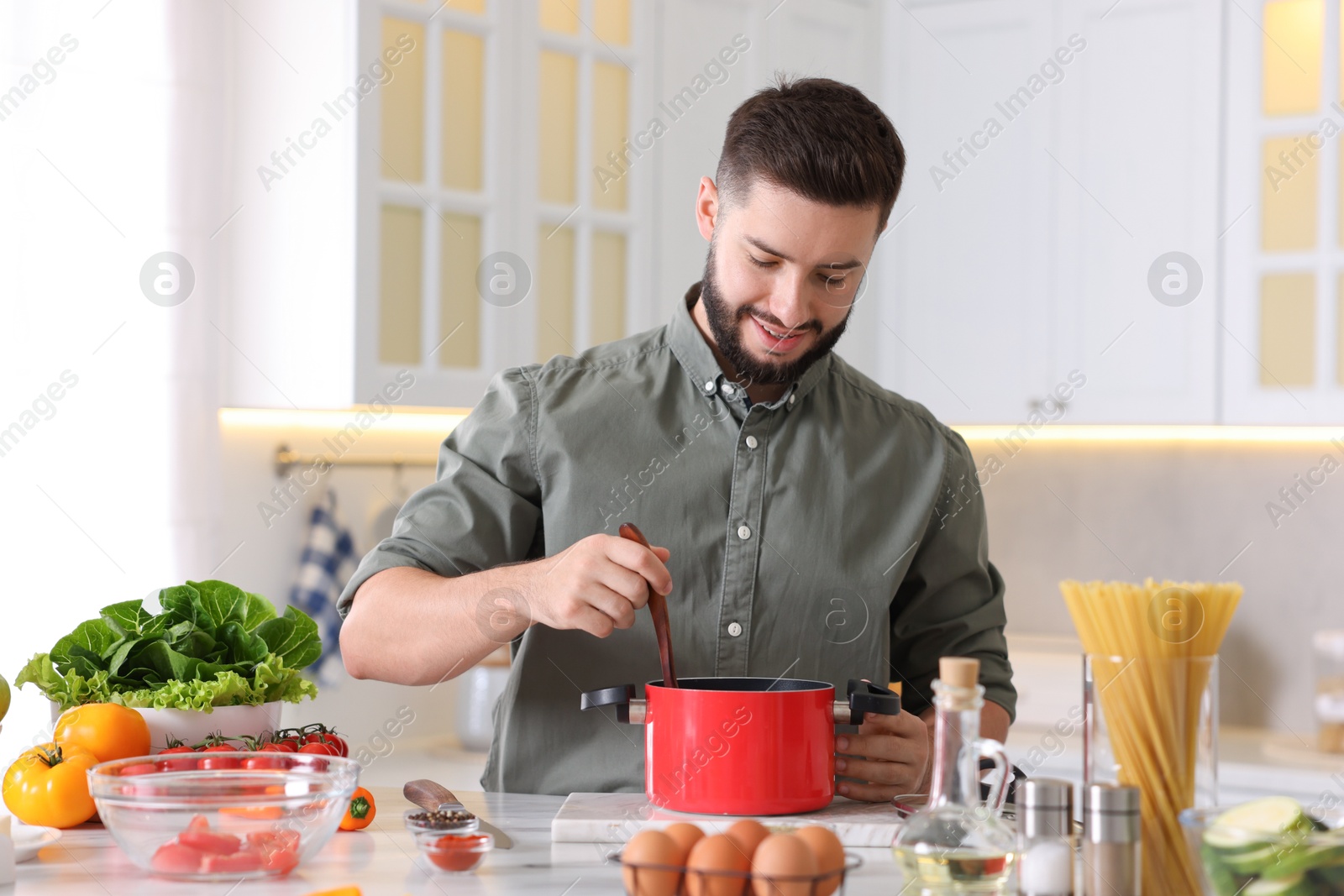 Photo of Smiling man cooking at table in kitchen