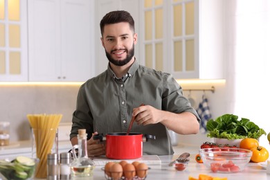 Photo of Smiling man cooking at table in kitchen