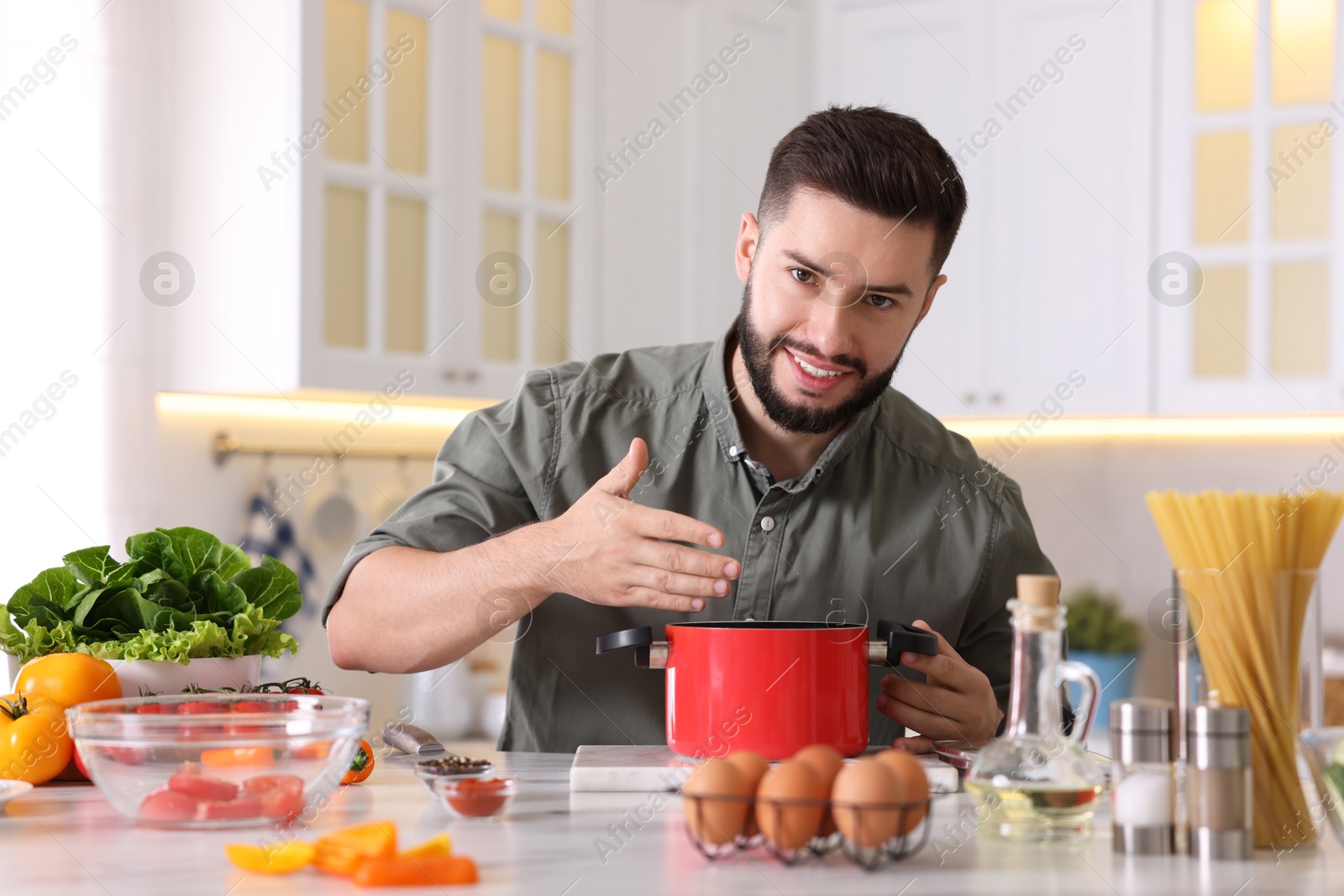 Photo of Smiling man cooking at table in kitchen