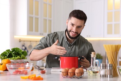 Photo of Smiling man cooking at table in kitchen