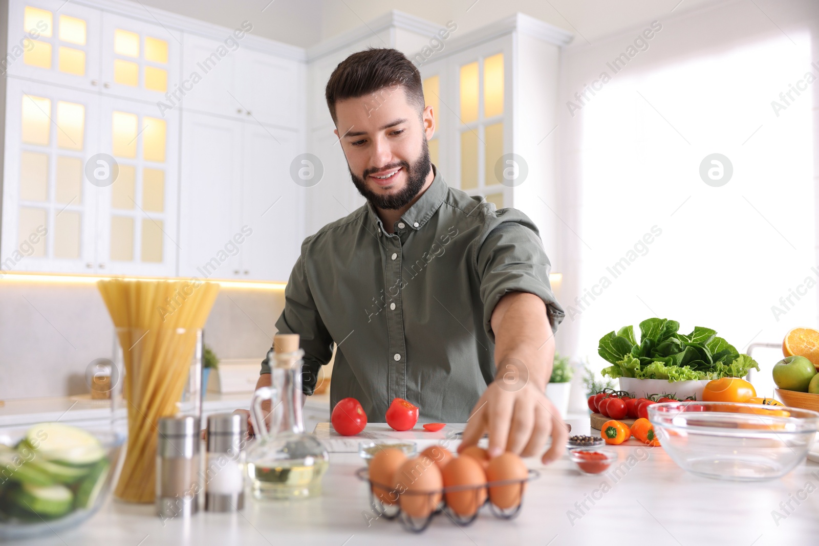 Photo of Smiling man cooking at table in kitchen