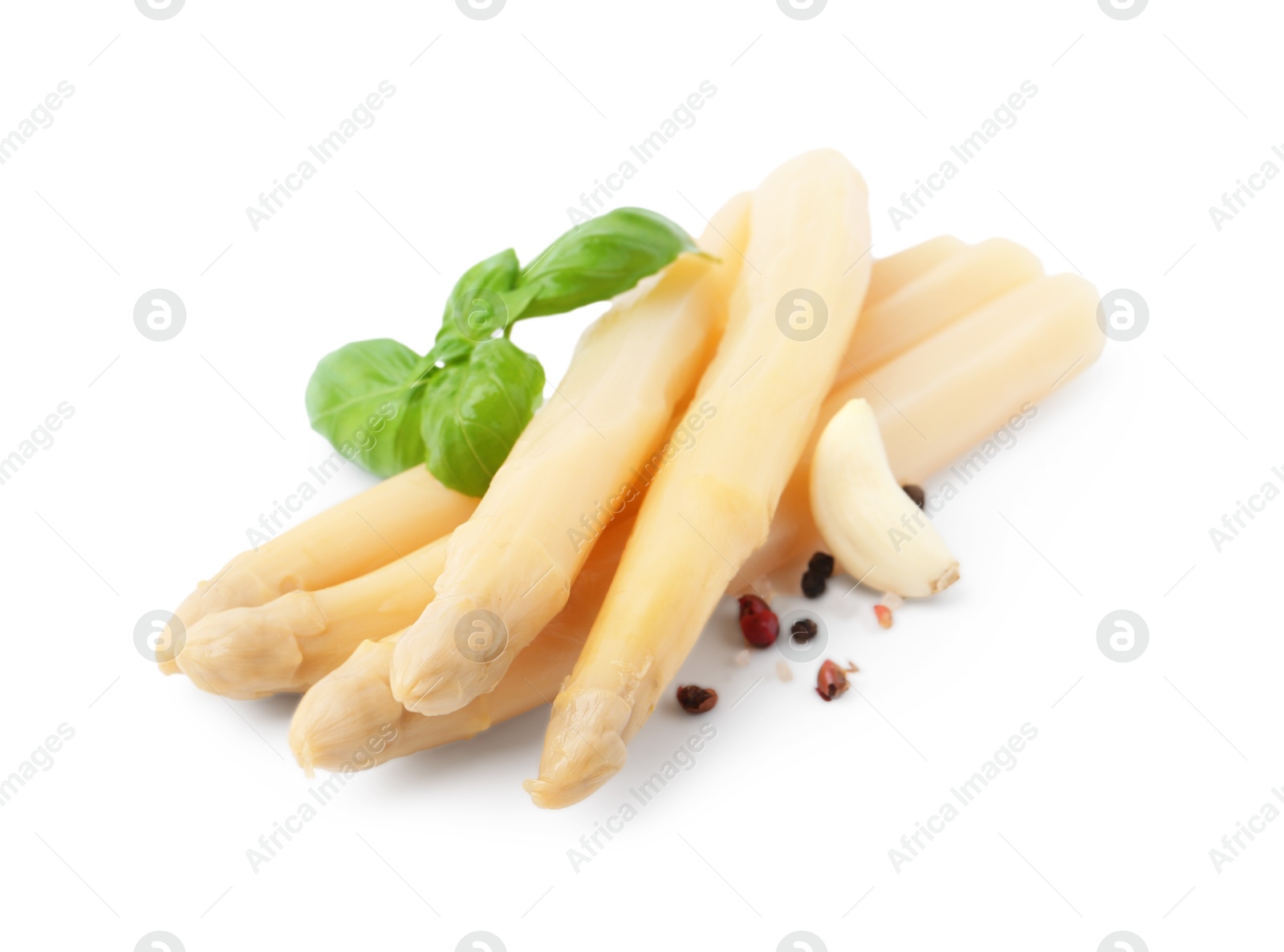 Photo of Spears of pickled asparagus with spices isolated on white