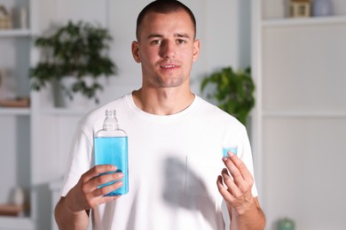 Photo of Man with bottle of mouthwash at home