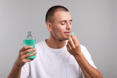 Photo of Man rinsing mouth with mouthwash on light grey background