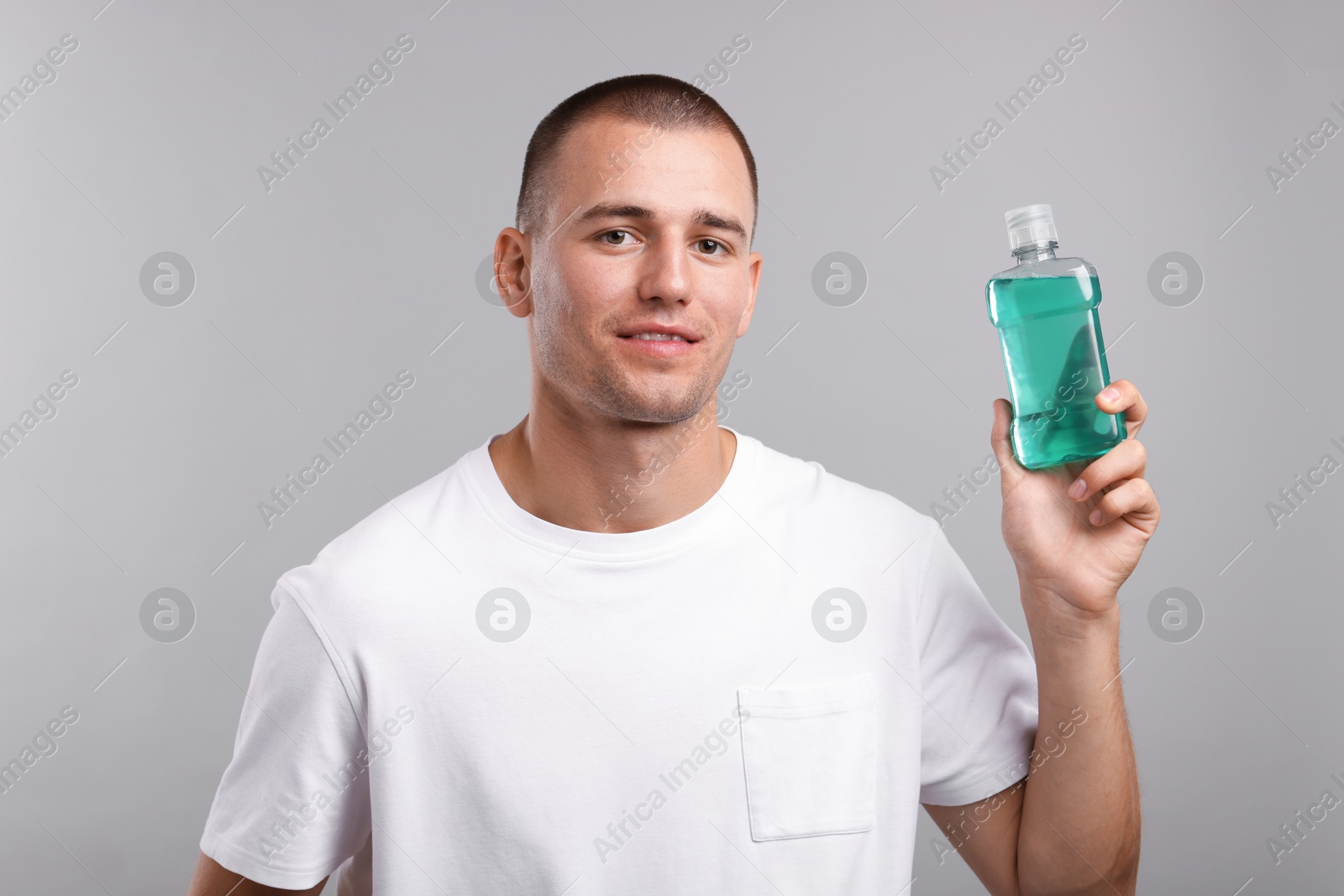 Photo of Man with bottle of mouthwash on light grey background