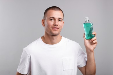 Photo of Man with bottle of mouthwash on light grey background