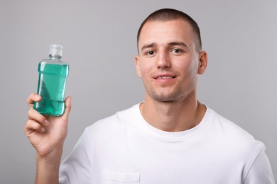 Photo of Man with bottle of mouthwash on light grey background