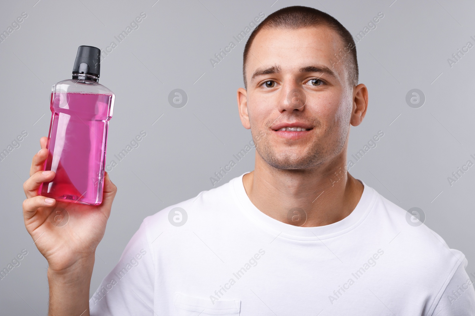 Photo of Man with bottle of mouthwash on light grey background
