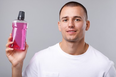 Photo of Man with bottle of mouthwash on light grey background