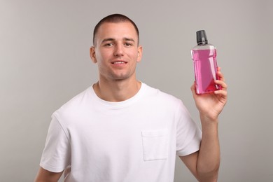 Photo of Man with bottle of mouthwash on light grey background