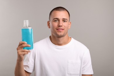 Photo of Man with bottle of mouthwash on light grey background