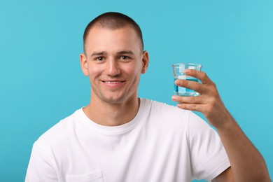 Photo of Man with glass of mouthwash on light blue background