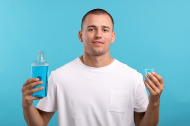 Photo of Man with bottle and cap of mouthwash on light blue background
