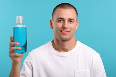 Photo of Man with bottle of mouthwash on blue background