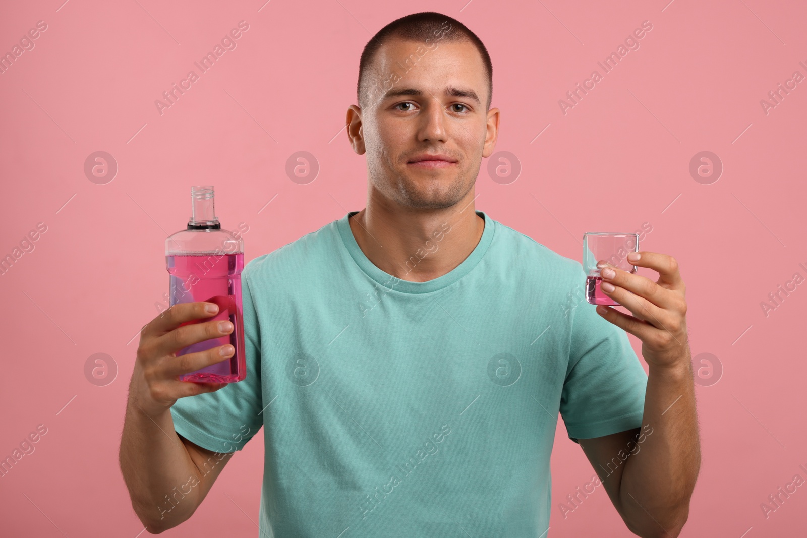 Photo of Man with bottle and glass of mouthwash on pink background