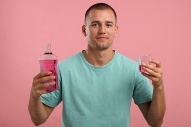 Photo of Man with bottle and glass of mouthwash on pink background