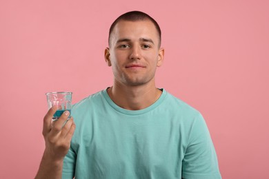 Photo of Man with glass of mouthwash on pink background