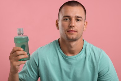Photo of Man with bottle of mouthwash on pink background