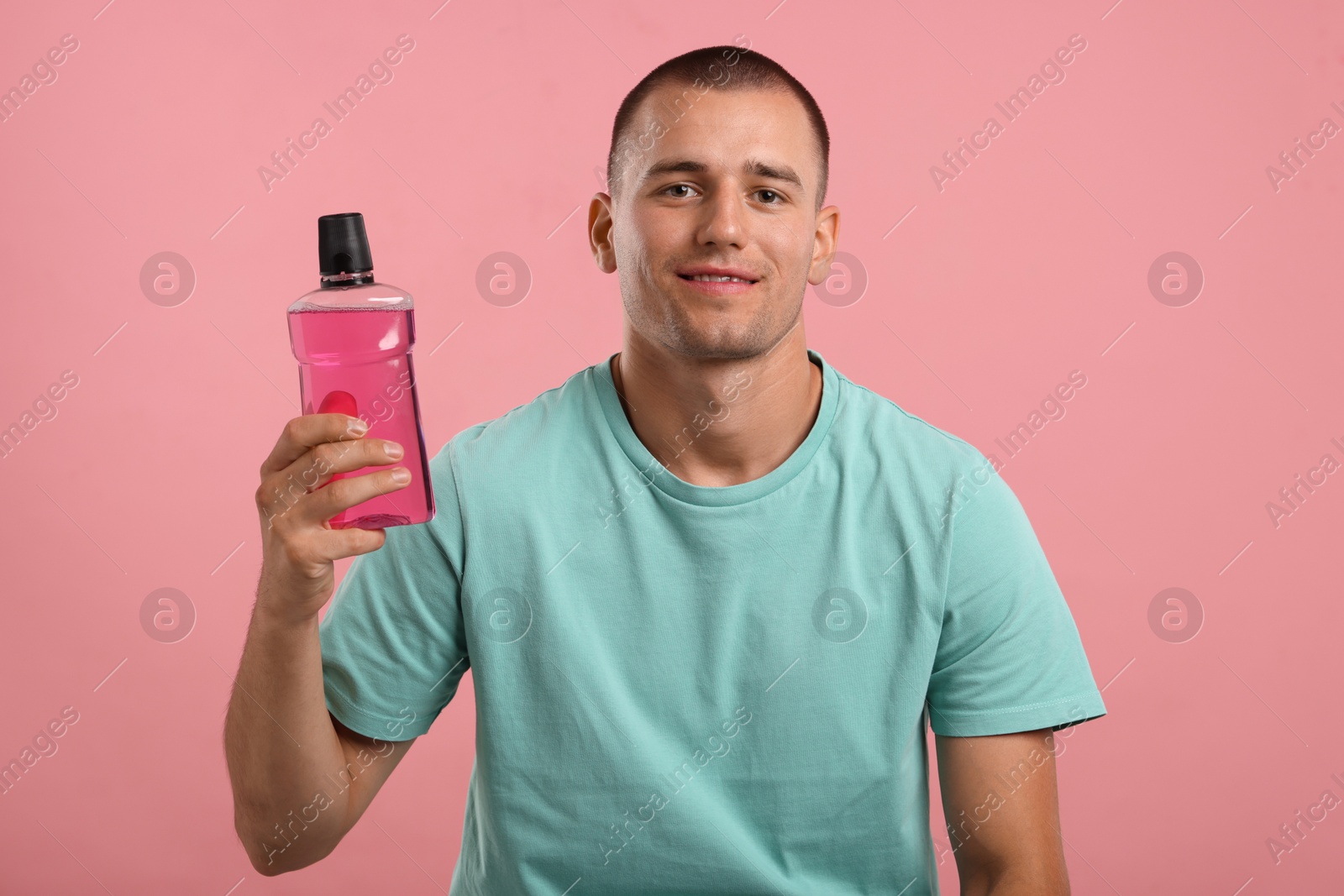 Photo of Man with bottle of mouthwash on pink background