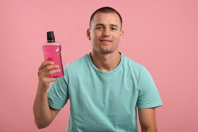 Photo of Man with bottle of mouthwash on pink background