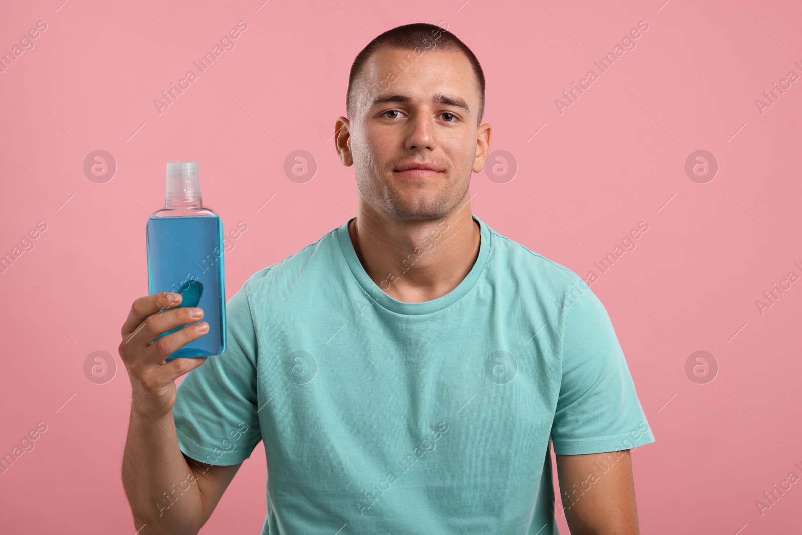 Photo of Man with bottle of mouthwash on pink background