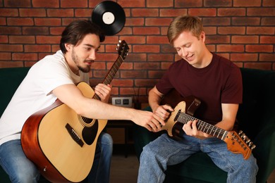 Photo of Tutor teaching man to play guitar indoors