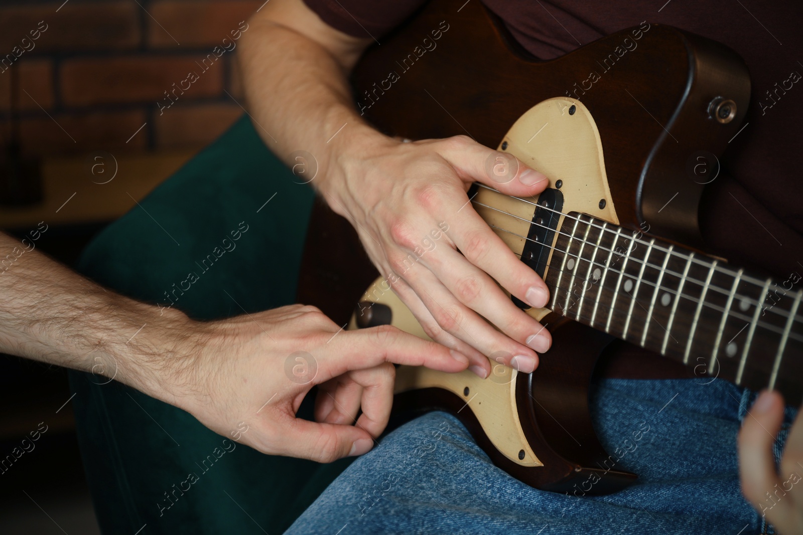 Photo of Tutor teaching man to play guitar at home, closeup