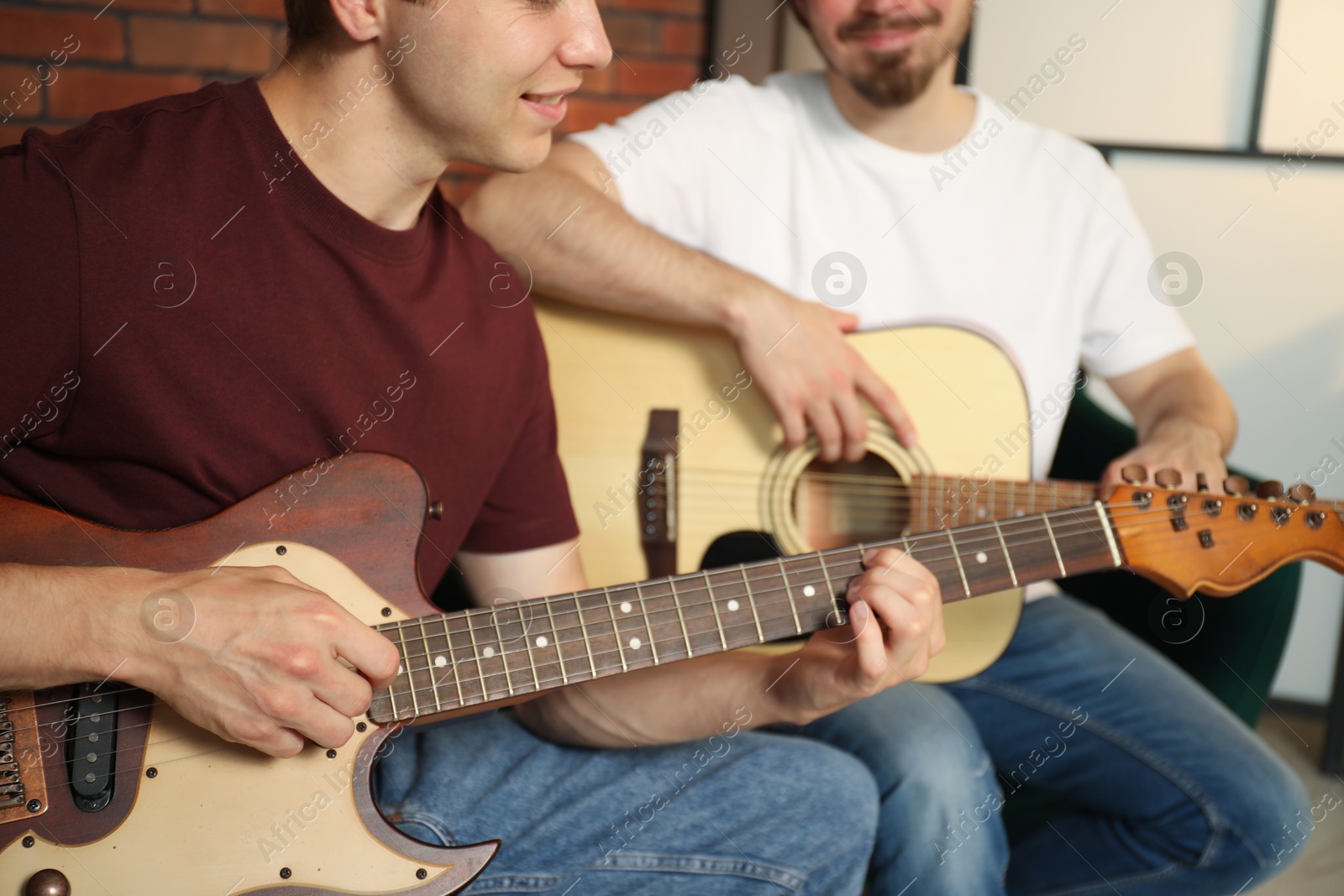 Photo of Tutor teaching man to play guitar at home, closeup